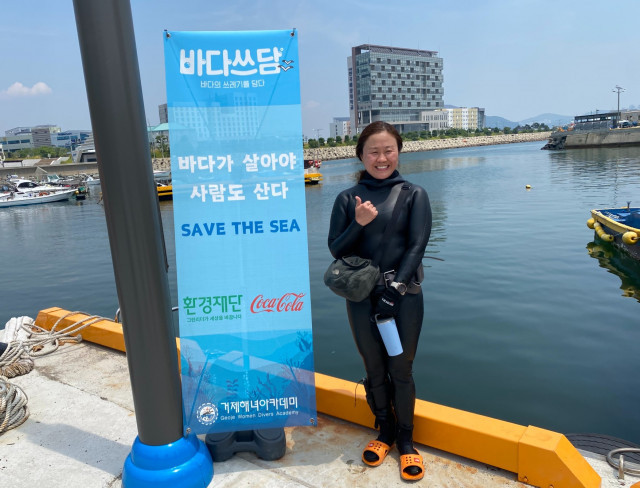 거제해녀아카데미 소속 활동가 해녀 신영 씨가 수중 정화활동을 통해 깨끗해진 바다를 배경으로 활짝 웃고 있다. (사진=환경재단 제공)