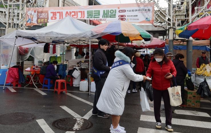 경상원이 여주한글시장을 방문한 도민들에게 '통큰 세일' 홍보물을 나눠주고 있다.